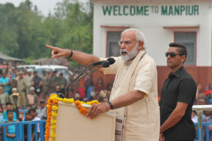 PM Modi speaking at public rally in Manipur with security and crowd in background